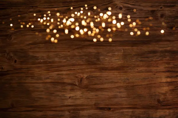 Festive golden luminous lights on rustic dark wood background for a christmas decoration