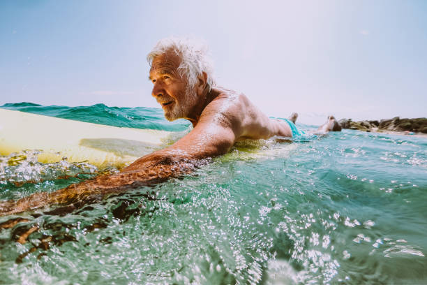 starszy mężczyzna surfing w morzu - surfing surf wave men zdjęcia i obrazy z banku zdjęć