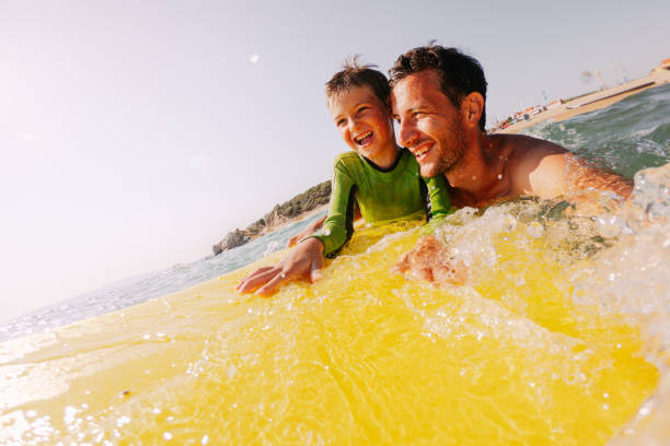 piccolo surfista carino e suo padre - competitive sport competition swimming wetsuit foto e immagini stock