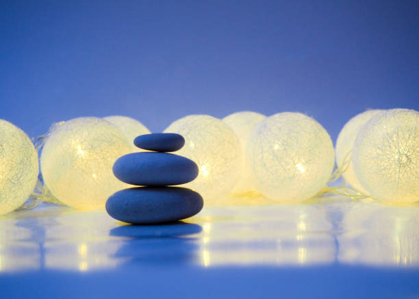 Stack of Zen stones on abstract dark background of Christmas garlands. Relax still Life with folded stones. Zen pebbles, stones, Spa-calm scenes to Christmas the soul of the imperturbable tranquility of the concept. copy space. pila de piedras zen sobre fondo oscuro abstracto de guirnaldas de navidad. relaja la vida con piedras dobladas. piedras zen, piedras, escenas de spa-calma a la navidad el alma de la tranquilidad imperturbable del concepto. copiar espacio