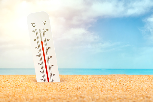 Thermometer standing in the sand at the beach in very hot weather