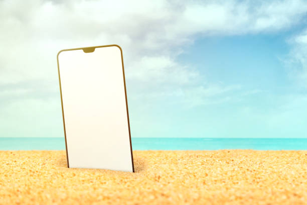 istock Mobile phone in the sand on the beach 1192081590