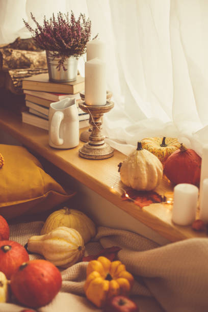 istock Flowers, candles and multi colored squash by the window 1192083101