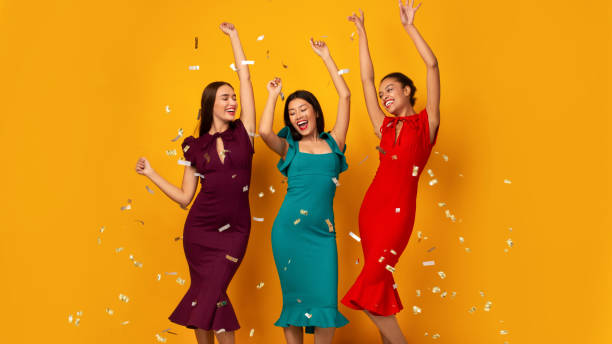 istock Three Happy Girls Dancing Under Falling Confetti Over Yellow Background 1192083160