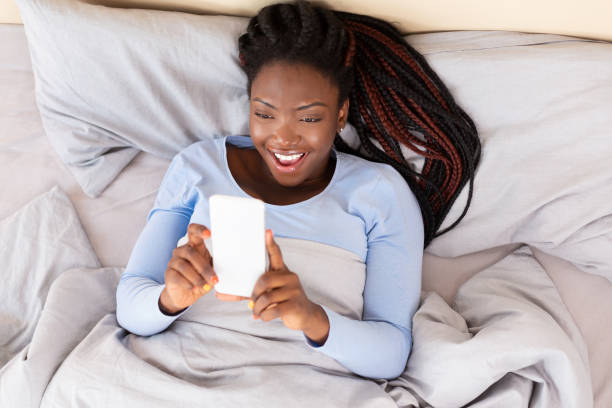 istock Hapy Girl Using Phone Holding Hands Above Lying In Bed 1192084233
