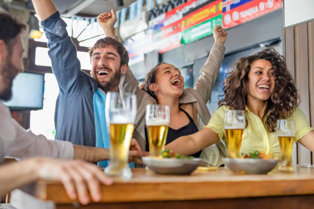 istock Four young people watching soccer game in pub cheering 1192084350