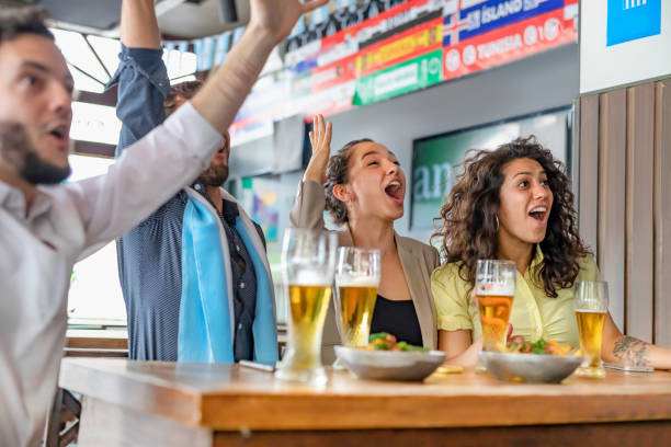 istock Four young people watching soccer game in pub cheering 1192084671