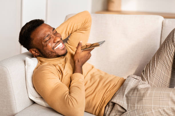 istock Man Using Phone Voice Assistant Lying On Couch At Home 1192085534