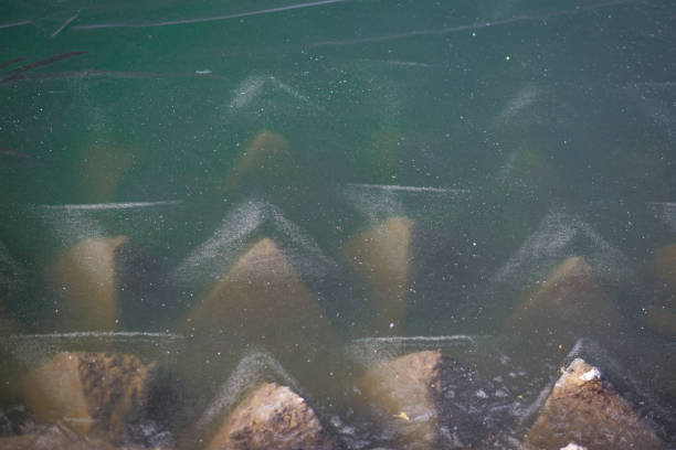 Texture of frozen and split ice on the lake. Turquoise ice on the lake froze on triangular breakwaters