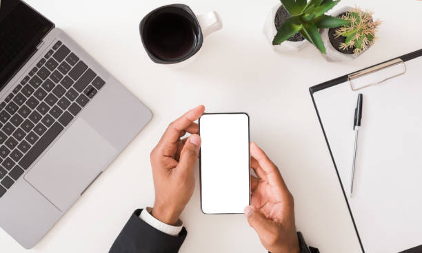 istock Businessman holding blank smartphone on workplace desk 1192087401