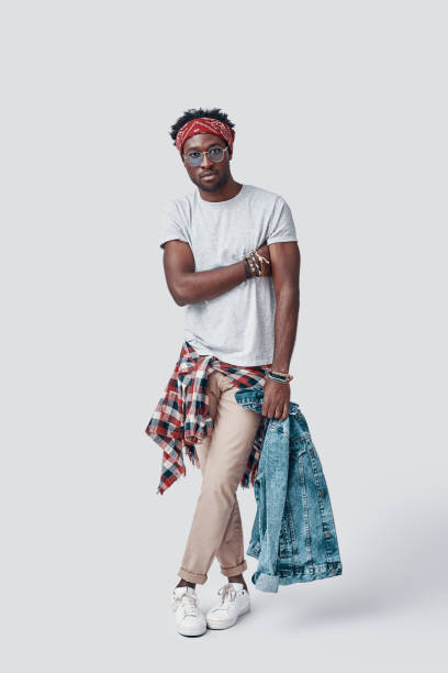 istock Full length of handsome young African man looking at camera while standing against grey background 1192089965