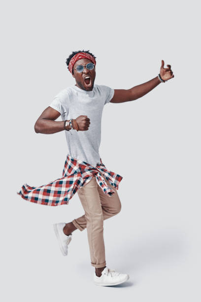 istock Full length of handsome young African man shouting while standing against grey background 1192090038