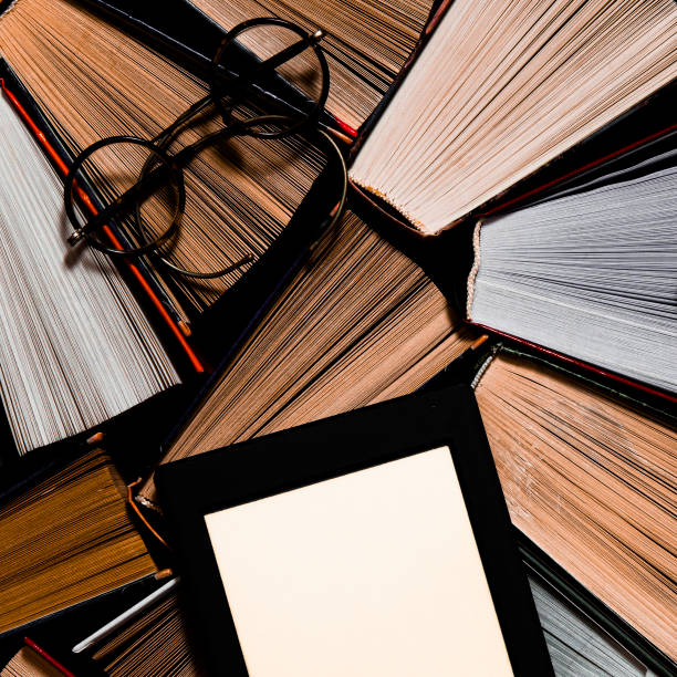 istock The e-book with a white screen lies on the open multi-colored books that lie on a dark background, close-up 1192090058
