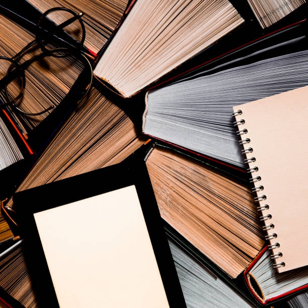 istock The e-book with a white screen lies on the open multi-colored books that lie on a dark background, close-up 1192090065