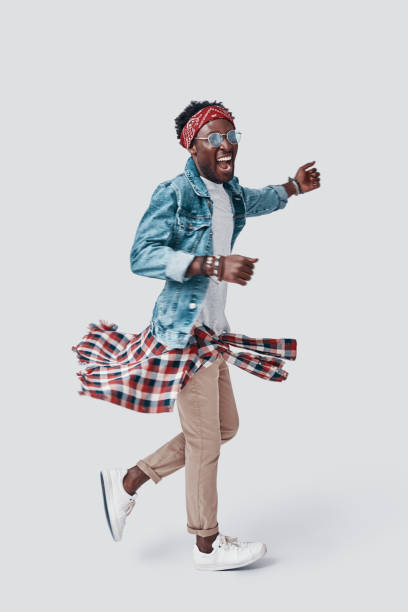 istock Full length of handsome young African man smiling while standing against grey background 1192090073