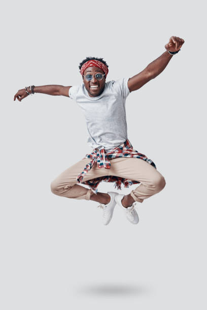 istock Full length of playful young African looking at camera and smiling while hovering against grey background 1192090303