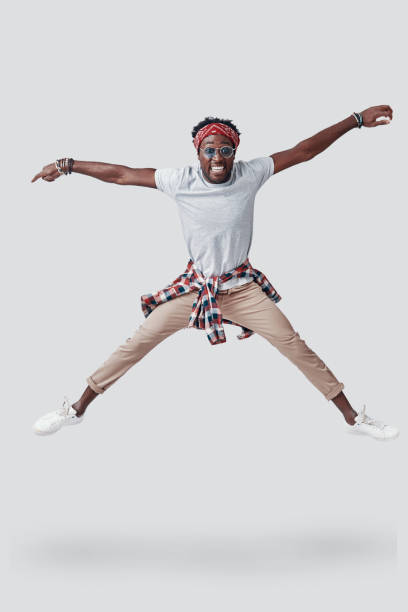 istock Full length of playful young African man smiling and looking at camera while hovering against grey background 1192090344