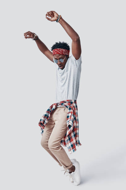 istock Full length of playful young African man dancing while standing against grey background 1192090565