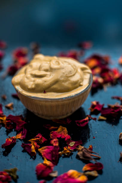 Ubtan/face mask/face pack of Multani mitti or fuller's earth on wooden surface in a glass bowl consisting of Multani mitti and rose water for the remedy or treatment of oily skin.On wooden surface. ubtan/máscara facial/paquete facial de mano multani o tierra más completa en superficie de madera en un cuenco de vidrio compuesto por manodema multani y agua de rosas para el remedio o tratamiento de la piel grasa. sobre superficie de madera.