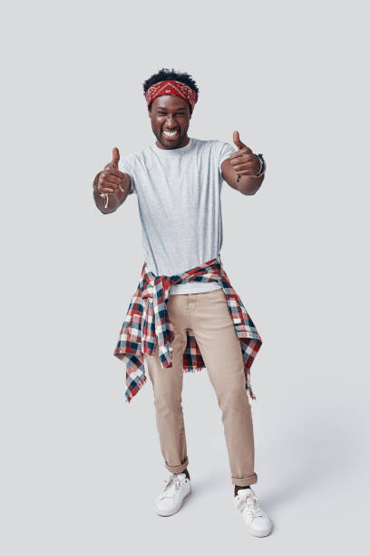 istock Full length of handsome young African man looking at camera and smiling while standing against grey background 1192092173