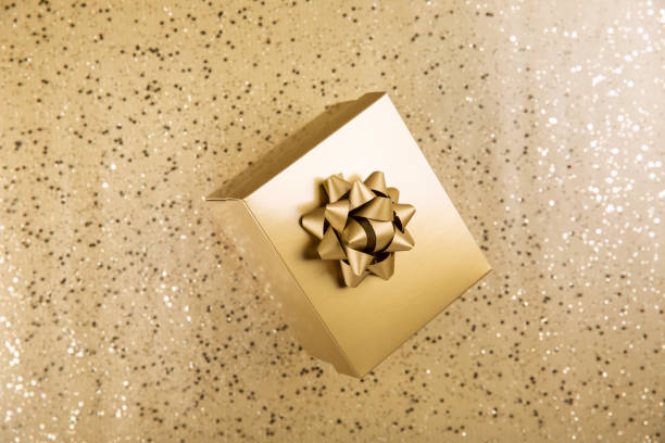 Expensive looking present wrapped in gold paper and red ribbon shallow depth of field. Add text to blank tag