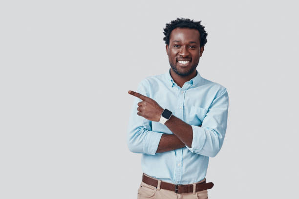 istock Handsome young African man pointing copy space and smiling while standing against grey background 1192092893