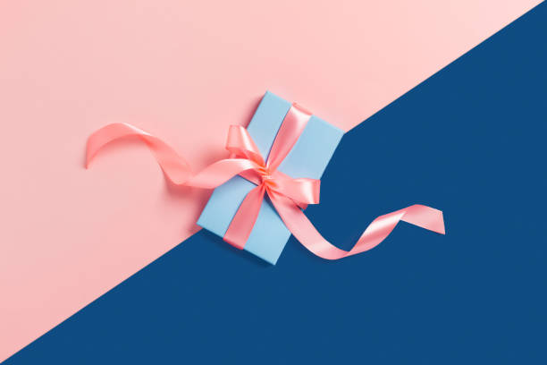 istock Holiday card. A blue box with a pink bow on two-toned background. 1192093329