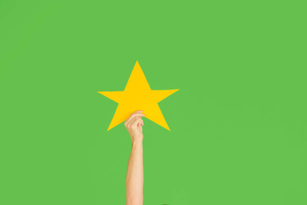 istock Hands holding the sign of star on green studio background 1192094500