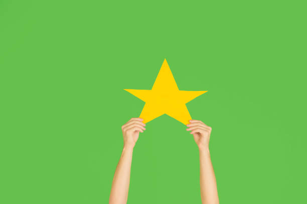 istock Hands holding the sign of star on green studio background 1192094511