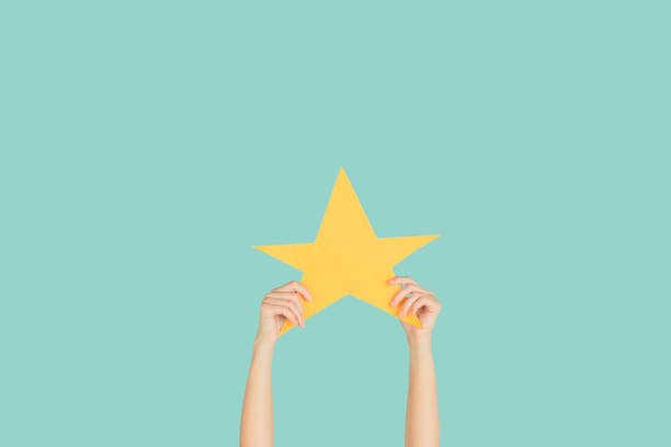 istock Hands holding the sign of star on blue studio background 1192094532