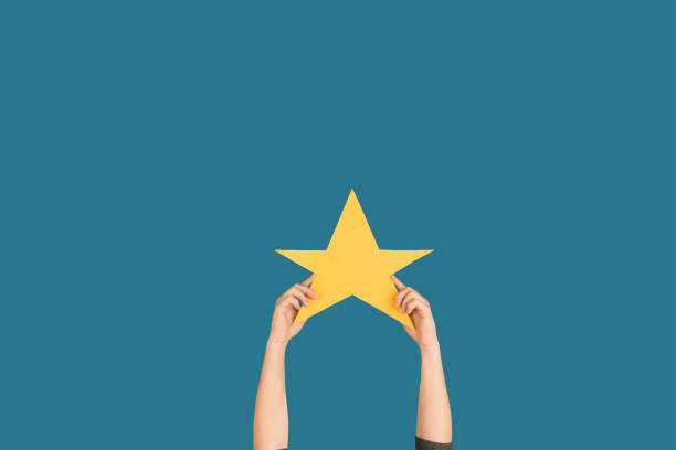 istock Hands holding the sign of star on blue studio background 1192094555