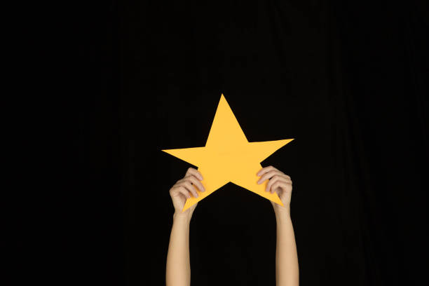 istock Hands holding the sign of star on black studio background 1192094643
