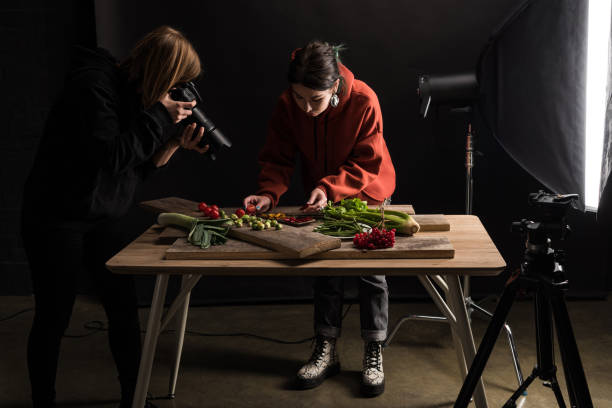 two photographers making food composition for commercial photography and taking photo on digital camera - food styling imagens e fotografias de stock