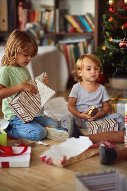 istock Kids opening Xmas presents. Children under Christmas tree with gift boxes. 1192096103