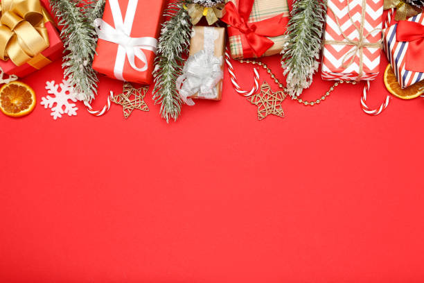 istock Gift boxes with christmas ornaments and fir tree branches on red background 1192096265