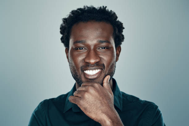 istock Handsome young African man looking at camera and smiling while standing against grey background 1192096318