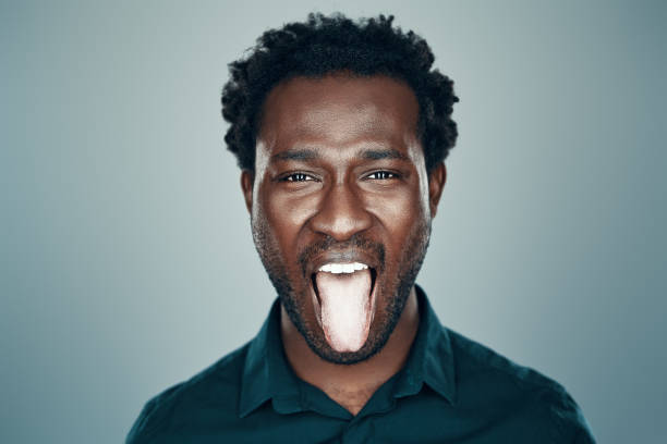 istock Handsome young African man looking at camera and sticking out tongue while standing against grey background 1192096343