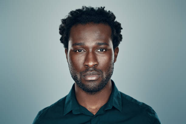 istock Handsome young African man looking at camera while standing against grey background 1192096493