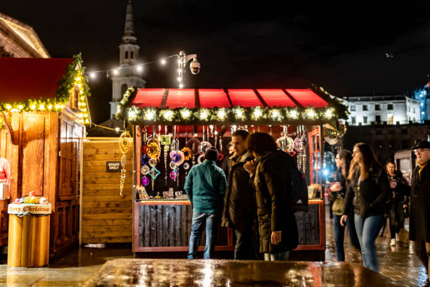 2019 Trafalgar Square Christmas Market 2019 Small Christmas Market in Trafalgar Square, London, England, UK. There are groups of tourists walking and talking as they pass by the market stalls. long exposure winter crowd blurred motion stock pictures, royalty-free photos & images