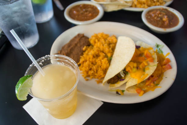 Margarita in plastic glass and tacos with sauces on black table