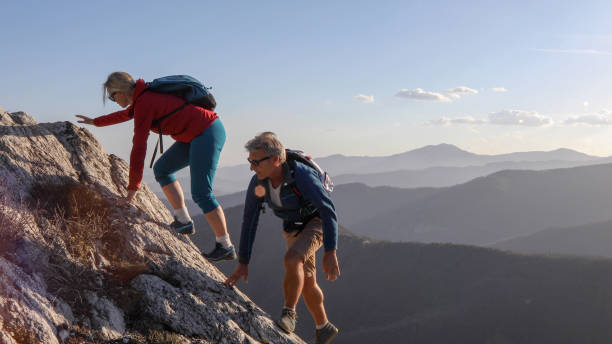 istock Mature couple scramble up mountain ridge 1192099316
