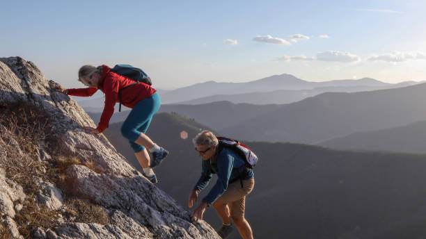 istock Mature couple scramble up mountain ridge 1192100192