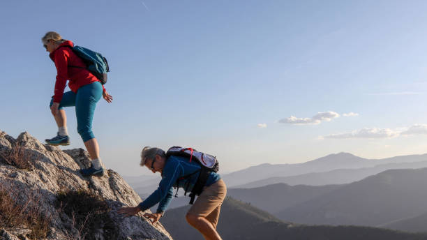 istock Mature couple scramble up mountain ridge 1192100340