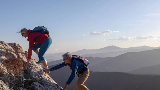 istock Mature couple scramble up mountain ridge 1192100371