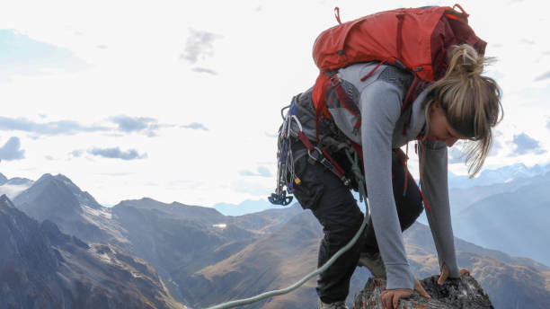 istock Female mountaineer scrambles up mountain ridge 1192100560