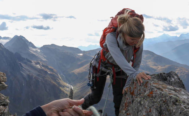 istock Female mountaineer scrambles up mountain ridge 1192100652