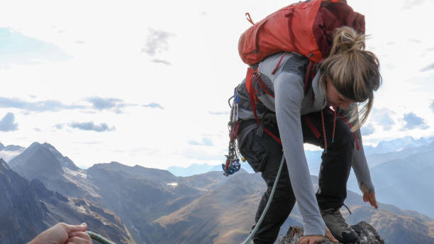 istock Female mountaineer scrambles up mountain ridge 1192100681