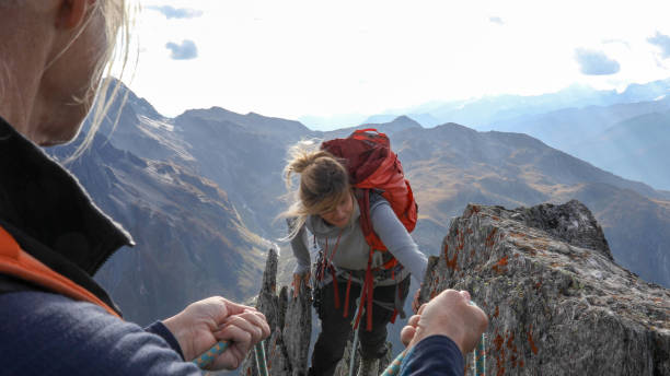 istock Female mountaineer scrambles up mountain ridge 1192100711