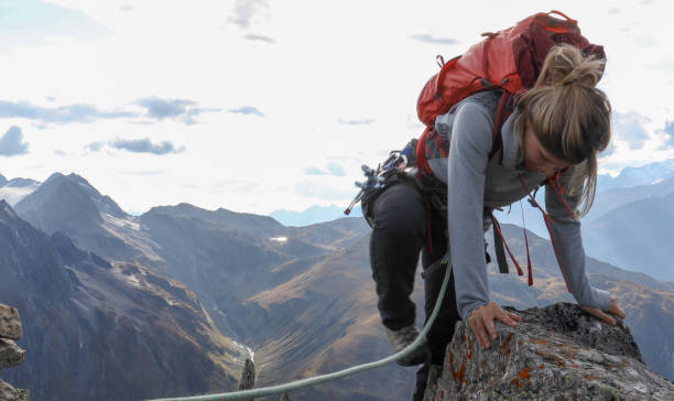 istock Female mountaineer scrambles up mountain ridge 1192100765
