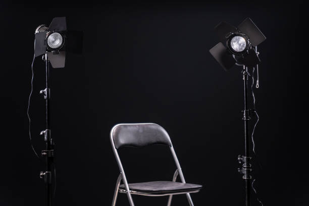 istock Black chair in front two two led spot lights, black background 1192101042